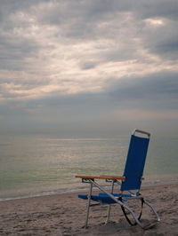 Blue beach chair facing the ocean and sky