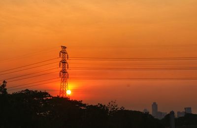 Silhouette electricity pylon against romantic sky at sunset