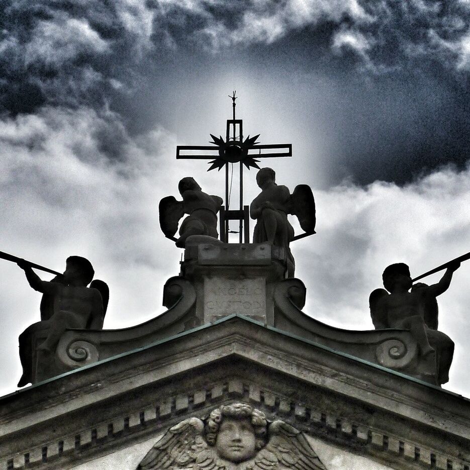 low angle view, religion, sky, human representation, cross, sculpture, statue, cloud - sky, spirituality, place of worship, art and craft, church, cloudy, art, creativity, built structure, architecture