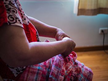 Midsection of woman sewing textile at home