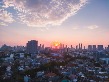 Aerial view of buildings in city against sky during sunset