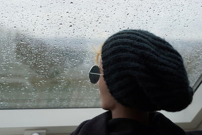 Portrait of child looking through window during rainy season