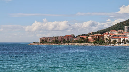 Scenic view of sea by townscape against sky