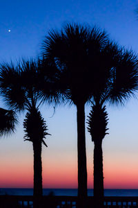 Low angle view of silhouette palm tree against sea at sunset