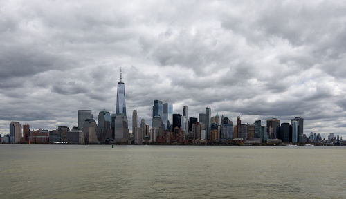 Sea and buildings in city against sky