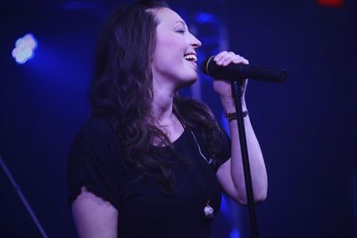 Woman singing while standing on stage