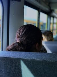 Rear view of woman sitting on vehicle seat in bus