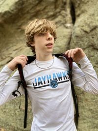 Portrait of young teen boy standing  against rock