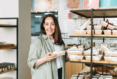 Adult smiling brunette woman forty years choosing sweets in cafe, woman having  in confectionery