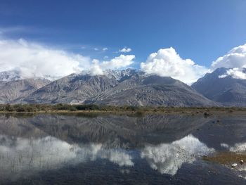 Scenic view of lake by snowcapped mountains against sky