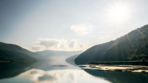 Scenic view of lake and mountains against sky on sunny day