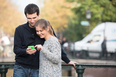 Smiling young couple using smart phone in city