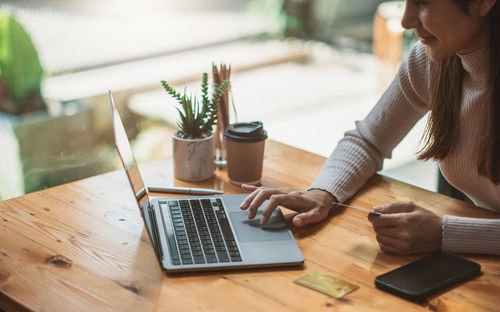 Midsection of woman using laptop on table