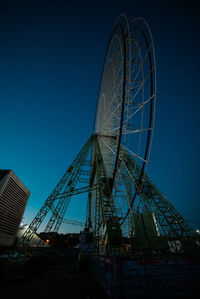 Low angle view of ferris wheel against blue sky