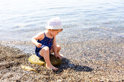 Little cute child girl playing on the seashore in summer