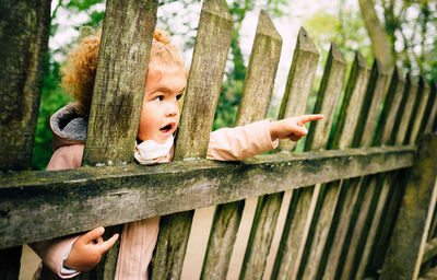 Child pointing by wooden fence