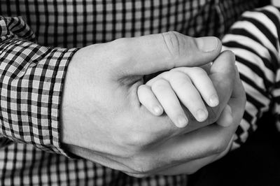 Midsection of father holding boy hand