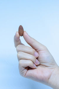 Close-up of hand holding ice cream over white background