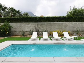 Swimming pool by trees against sky