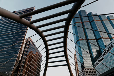 Low angle view of modern buildings against sky seen through bridge at sathon district