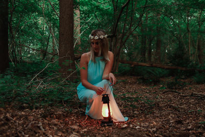 Full length of young woman crouching in forest