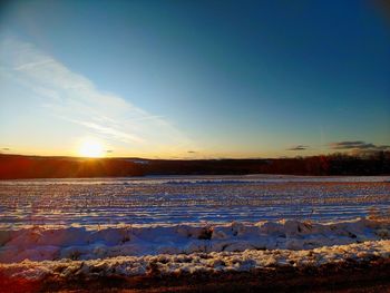 Scenic view of snow covered field against sky during sunset