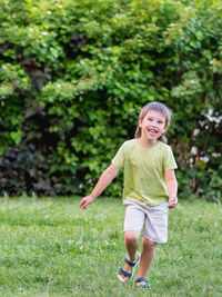 Laughing kid runs on grass lawn at backyard. childhood. vacation. cheerful child plays outdoors. 