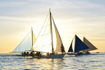 Boats sailing in sea at sunset