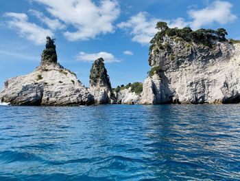 Rock formation by sea against blue sky