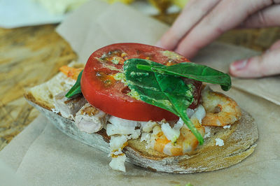 Cropped image of hand by open faced sandwich on table