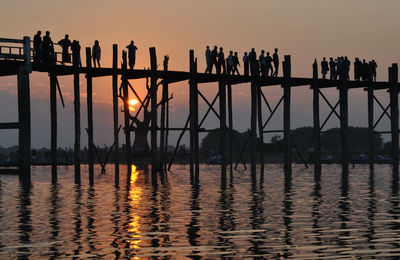 Silhouette of people walking on pier over lake