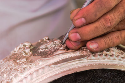 Cropped hand of artist carving metal in workshop