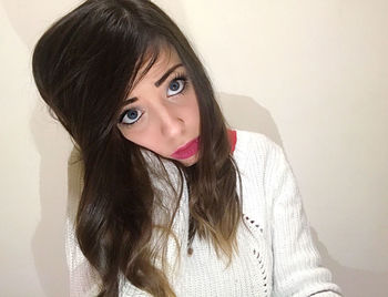 Portrait of young woman against wall