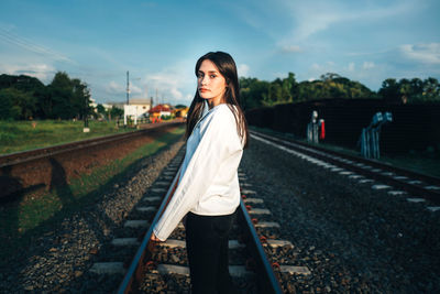 Portrait of young woman standing on railroad track