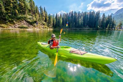 Mid adult man kayaking on lake against sky