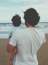 Rear view of couple on beach against sky