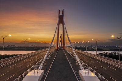 Illuminated bridge against sky during sunset