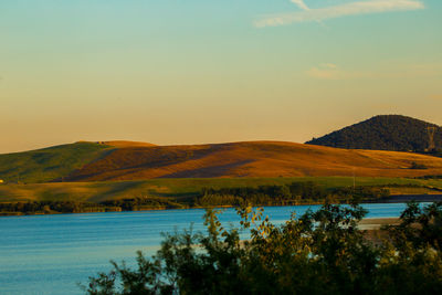 Scenic view of lake by mountains against sky