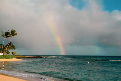 Scenic view of sea against rainbow in sky