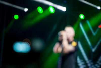 Defocused image of man standing in illuminated lights