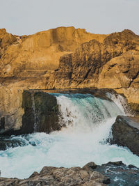 Scenic view of waterfall against sky