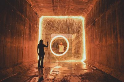 Man playing with wire wool while looking at woman in tunnel