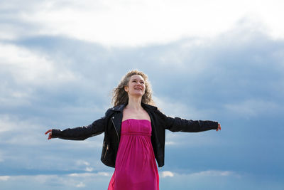 Woman outstretched arms to the sides against the background of a gloomy sky