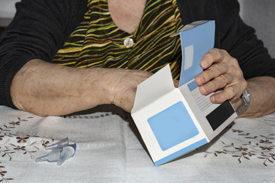 Midsection of man holding mobile phone while sitting on table