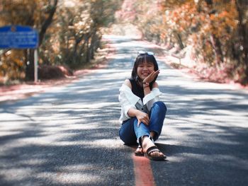 Portrait of smiling young woman sitting on road