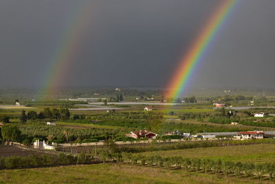 Scenic view of rainbow over field against sky