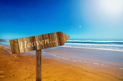 Close-up of heaven sign at beach against clear blue sky