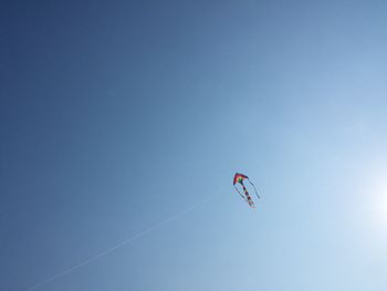 Low angle view of paragliding against clear blue sky