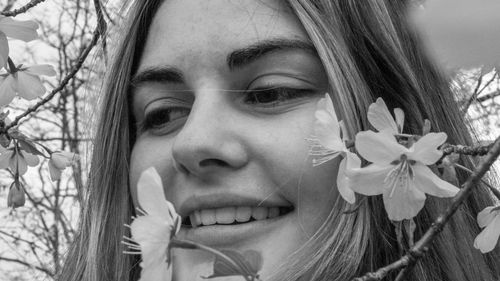 Close-up portrait of smiling young woman against plants