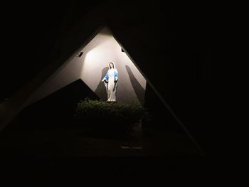 Man standing by illuminated lamp at night